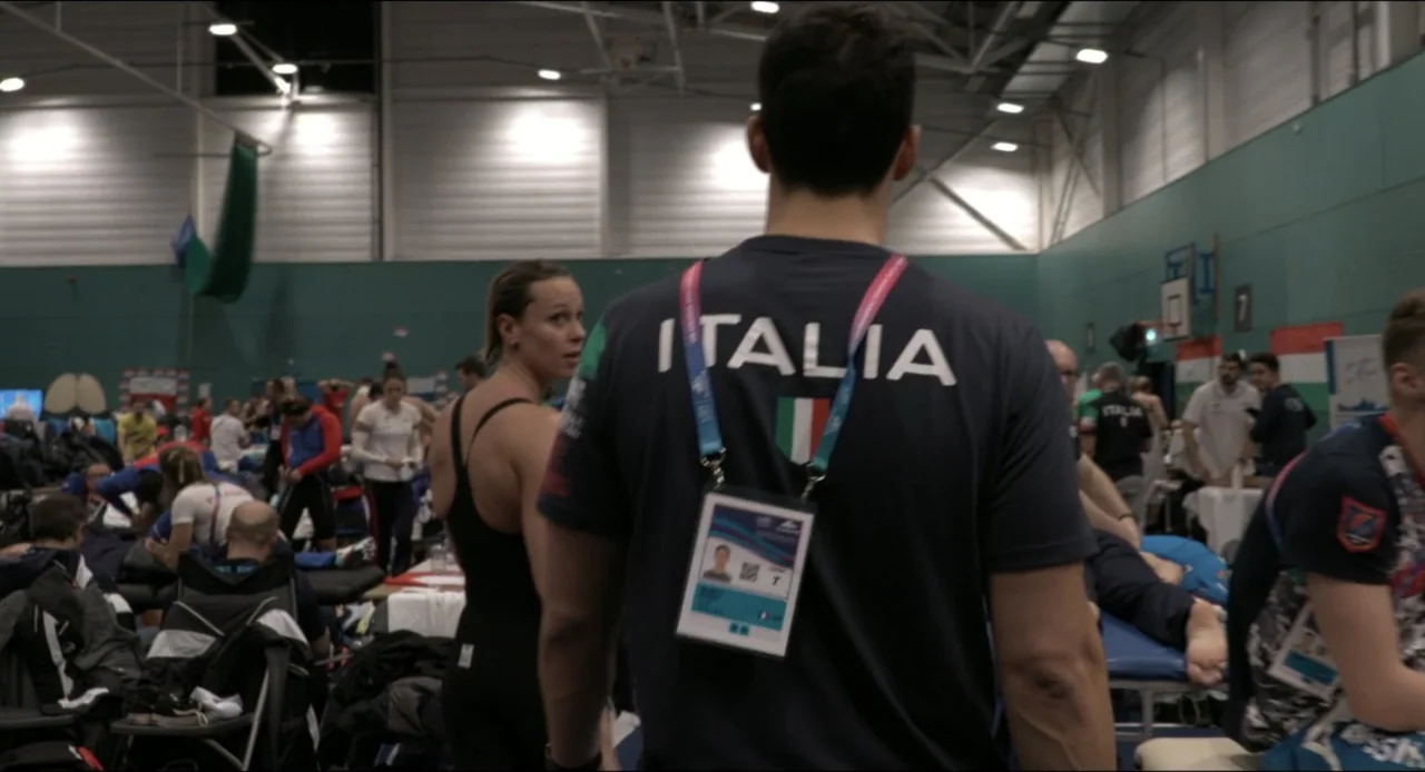 Federica Pellegrini - Underwater (2022) movie still: medium — An indoor athletic training facility features rows of massage tables and active…
