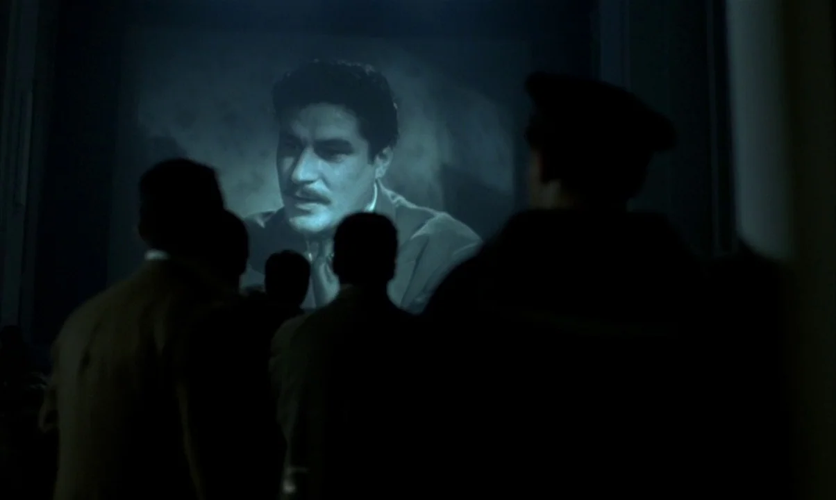 Cinema Paradiso (1988) movie still: wide — A dark movie theater interior with multiple silhouettes of patrons facing a large screen. The screen…