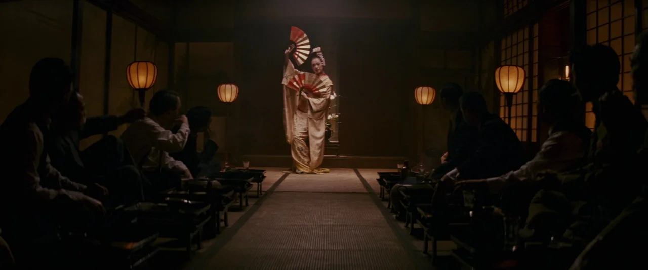 Memoirs of a Geisha (2005) movie still: wide — A dimly lit room features traditional tatami mats and wooden screens with glowing paper lanterns. A…