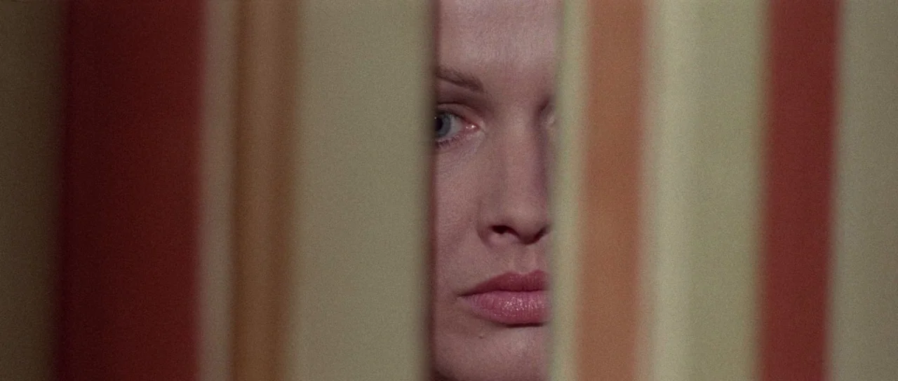 The Case of the Scorpion’s Tail (1971) movie still: closeup — A close-up view through a sliver between vertically oriented fabric stripes of a…
