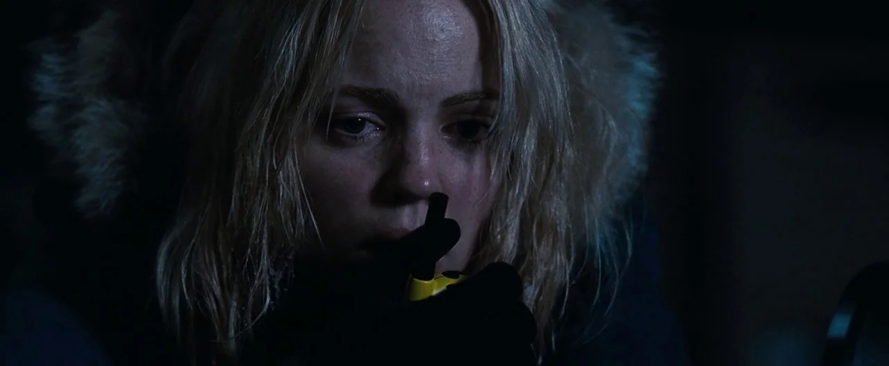 30 Days of Night (2007) movie still: closeup — A dark outdoor setting at night surrounds a woman wearing a heavy winter hood. She holds a small…