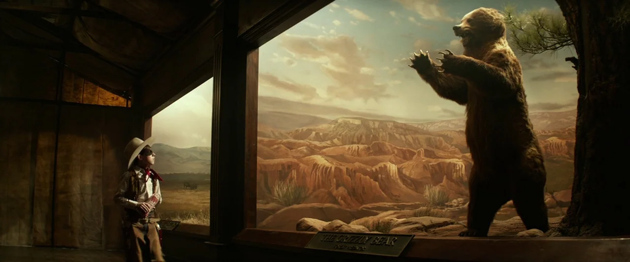 The Lone Ranger (2013) movie still: wide — A dimly lit museum hall features large glass cases containing natural history displays. A boy dressed as…