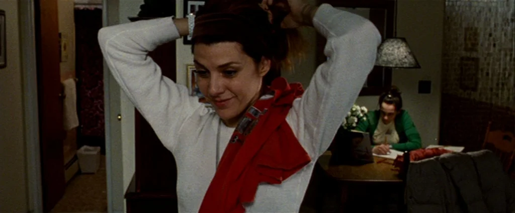 The Wrestler (2008) movie still: medium — A domestic space with soft lighting and a table visible in the background. A woman in a white long-sleeve…