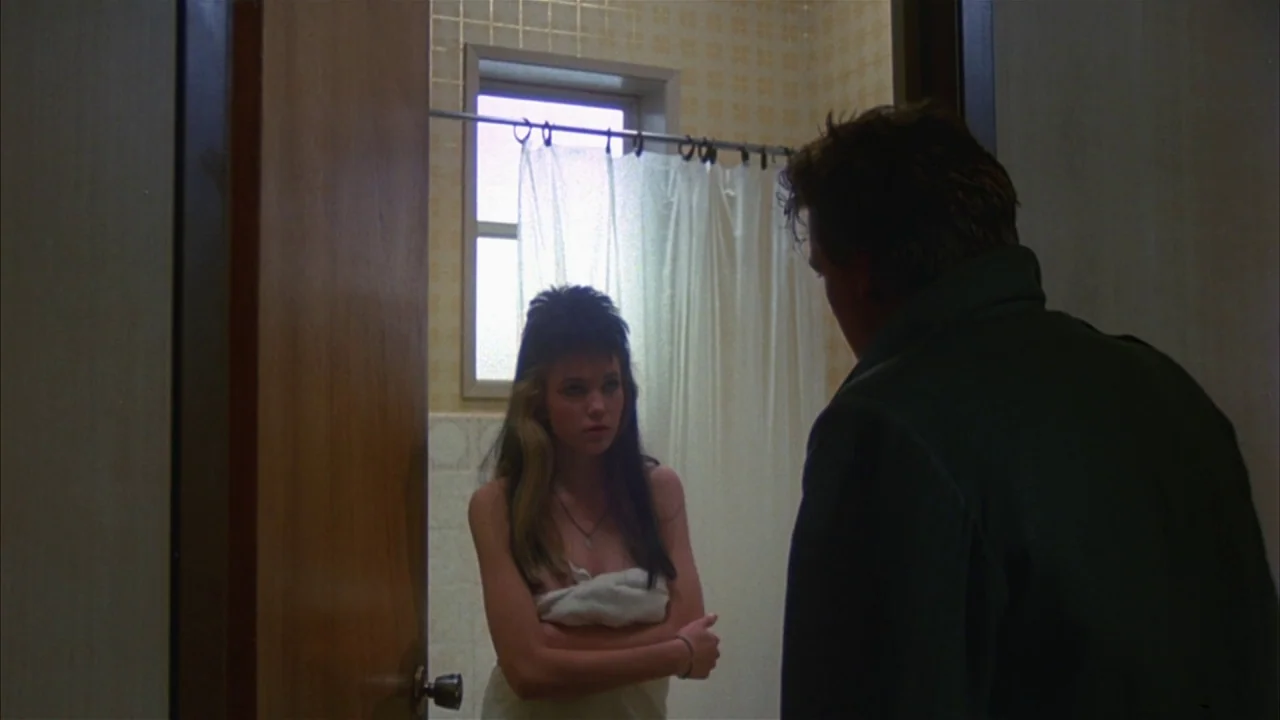 Ladies and Gentlemen, the Fabulous Stains (1985) movie still: medium — A bathroom with square tan tiles and a shower curtain behind a standing…