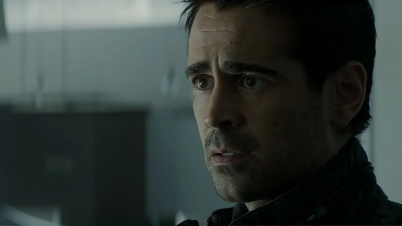 Total Recall (2012) movie still: closeup — A dimly lit modern interior space features a man positioned near a window. A man with dark stubble and a…
