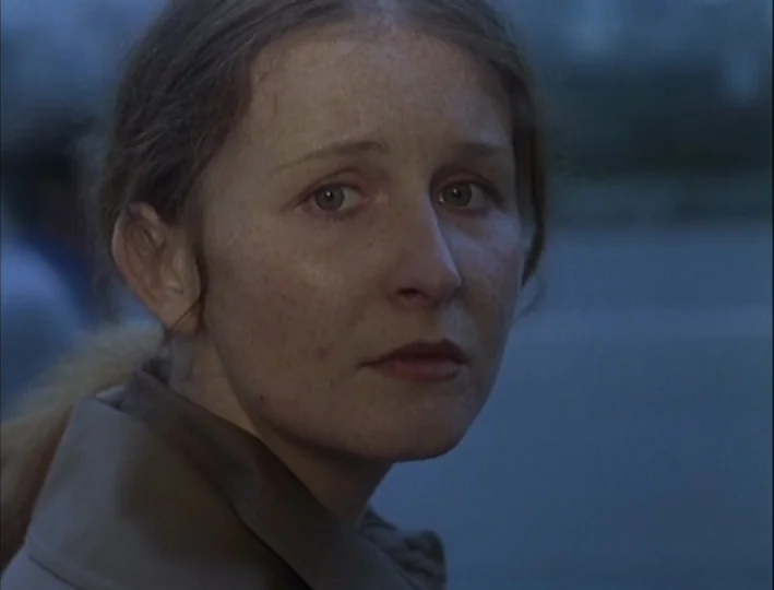 Camera Buff (1979) movie still: closeup — An outdoor area at dusk features a woman against a blurred neutral background. The subject is framed in a…