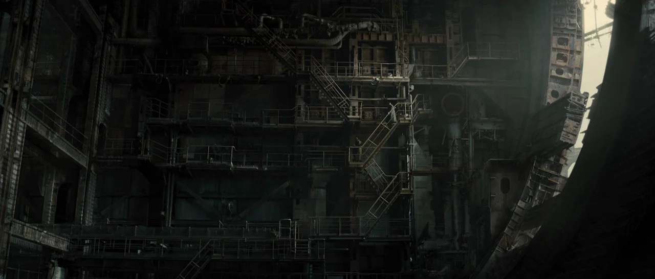 Blade Runner 2049 (2017) movie still: wide — A massive industrial structure features multiple levels of iron walkways and complex metal piping. The…