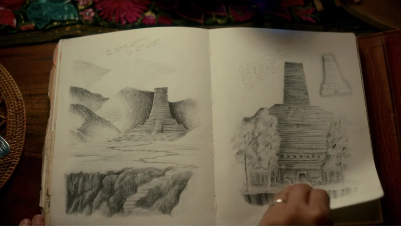Dora and the Lost City of Gold (2019) movie still: closeup — An open journal lies on a wooden surface with drawings of ancient pyramids. A hand is…