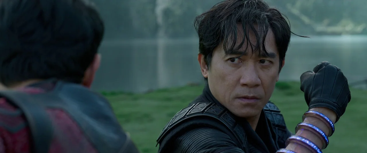 Shang-Chi and the Legend of the Ten Rings (2021) movie still: medium — A lakeside setting with a blurred green landscape and calm water in the…