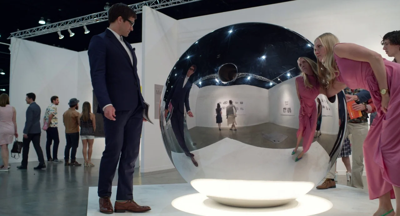 Velvet Buzzsaw (2019) movie still: medium — A minimalist white-walled art gallery exhibition space contains a large, spherical reflective sculpture.…