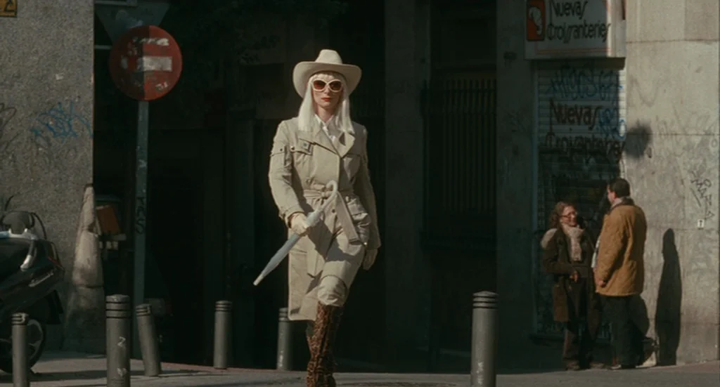 The Limits of Control (2009) movie still: fullbody — A sunlit urban sidewalk features graffiti-covered walls and a red circular traffic sign. A…