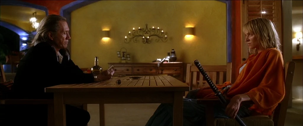 Kill Bill Vol. 2 (2004) movie still: medium — A spacious room features yellow plaster walls, arched doorways, and a wooden table. A man and a woman…