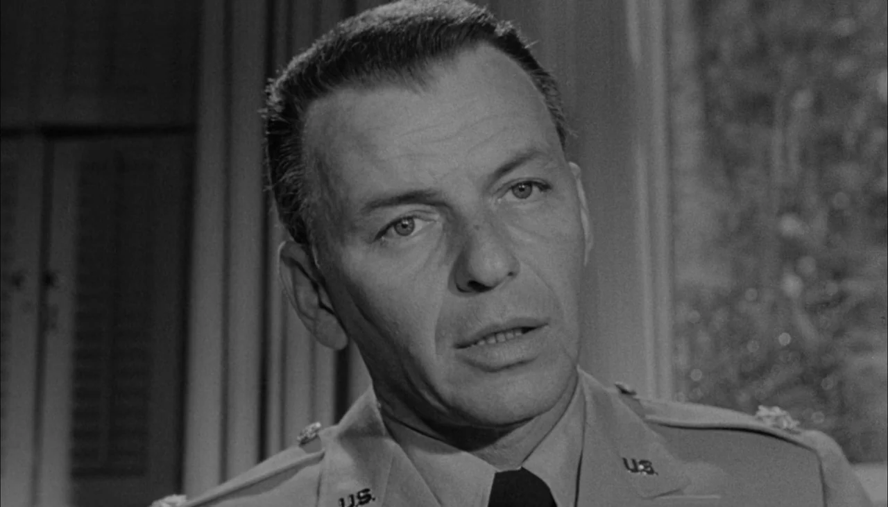 The Manchurian Candidate (1962) movie still: closeup — An interior space features wooden shutters and a framed artwork on the wall. A middle-aged…