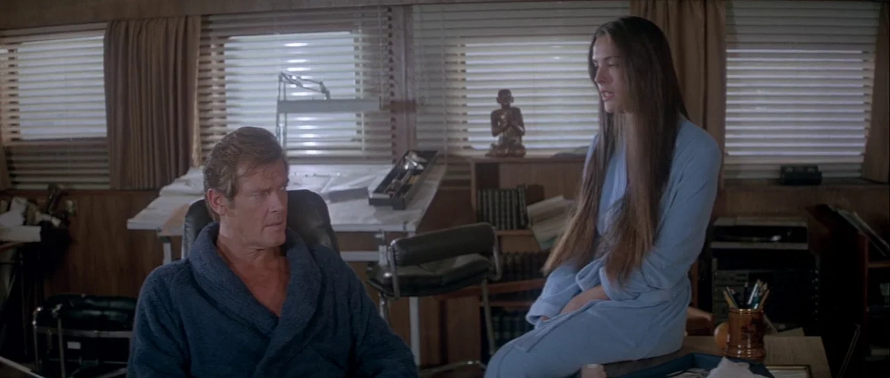 For Your Eyes Only (1981) movie still: medium — A wood-paneled room features window blinds, a desk, and a small decorative statue. A man in a blue…
