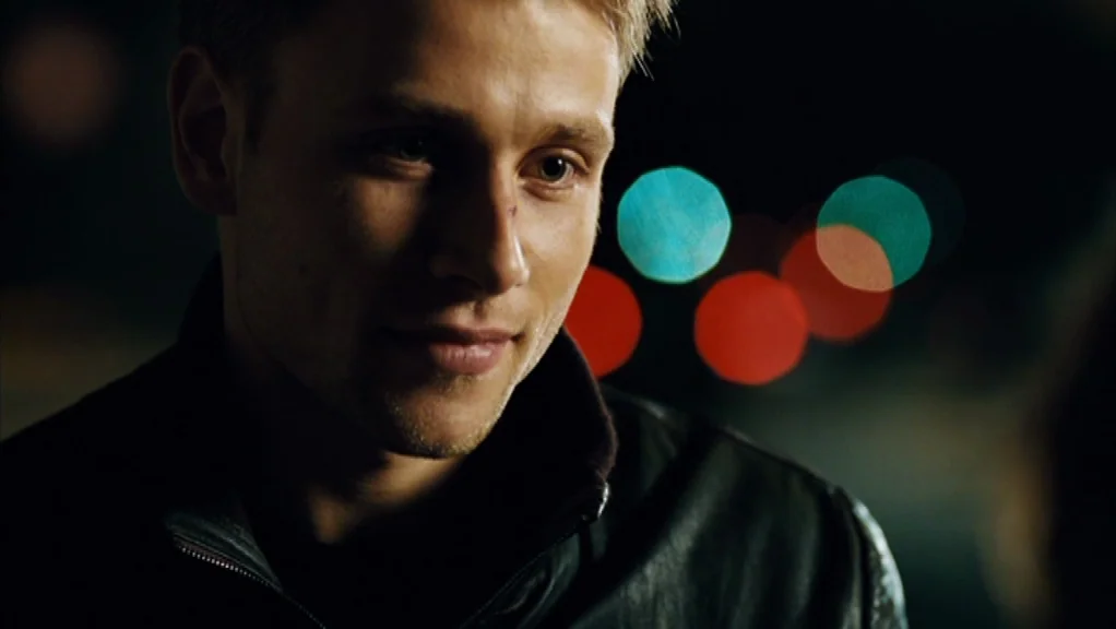 We Are The Night (2010) movie still: A young man is captured in an intimate, medium-close shot at night, his expression one of quiet affection or…
