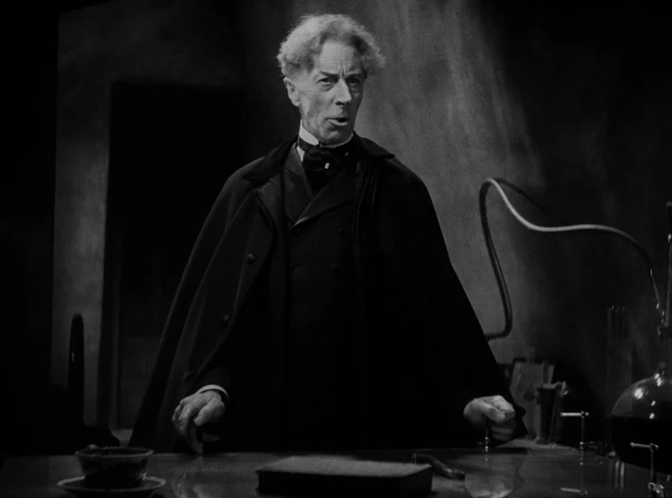 The Bride of Frankenstein (1935) movie still: medium — A dimly lit room contains a workbench with scientific glass apparatuses. An older man stands…