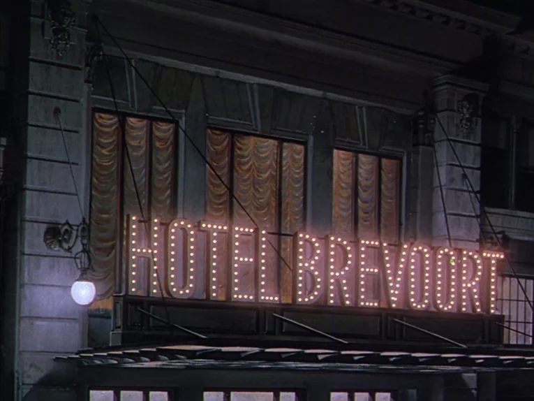 Annie Get Your Gun (1950) movie still: establishing — The exterior facade of a classic hotel features a prominent glowing neon sign. Large windows…