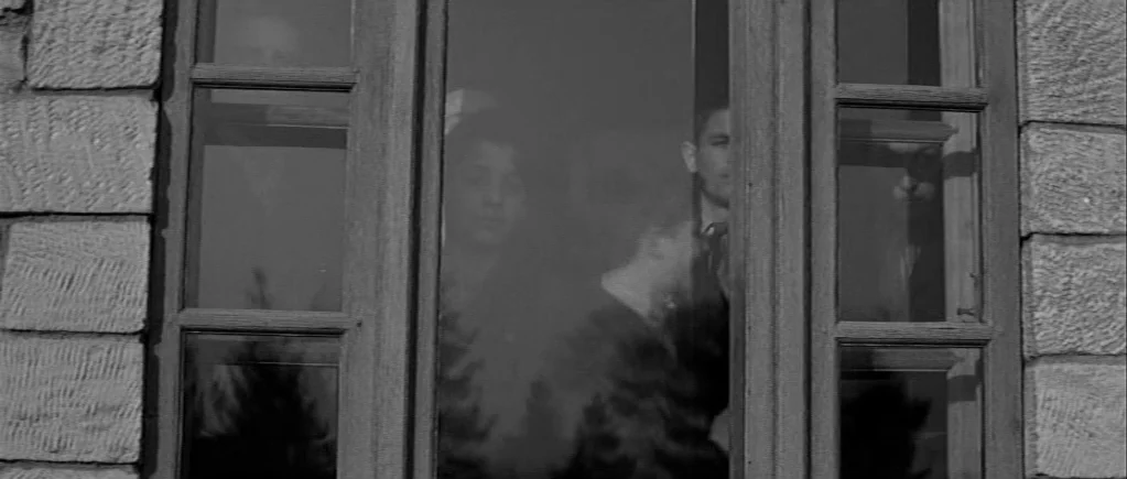 The 400 Blows (1959) movie still: medium — A stone building exterior features a wooden-framed window with multiple panes of glass. Several young…