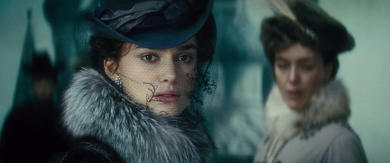 Anna Karenina (2012) movie still: medium — A dimly lit, grand interior features ornate architectural details obscured by soft, cool-toned shadows.…