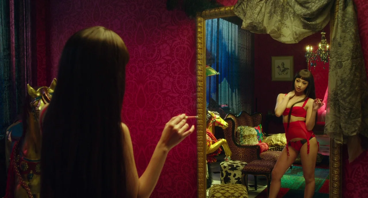 Helter Skelter (2012) movie still: medium — An opulent room with deep magenta patterned wallpaper and gold-framed furniture. A woman in red lingerie…