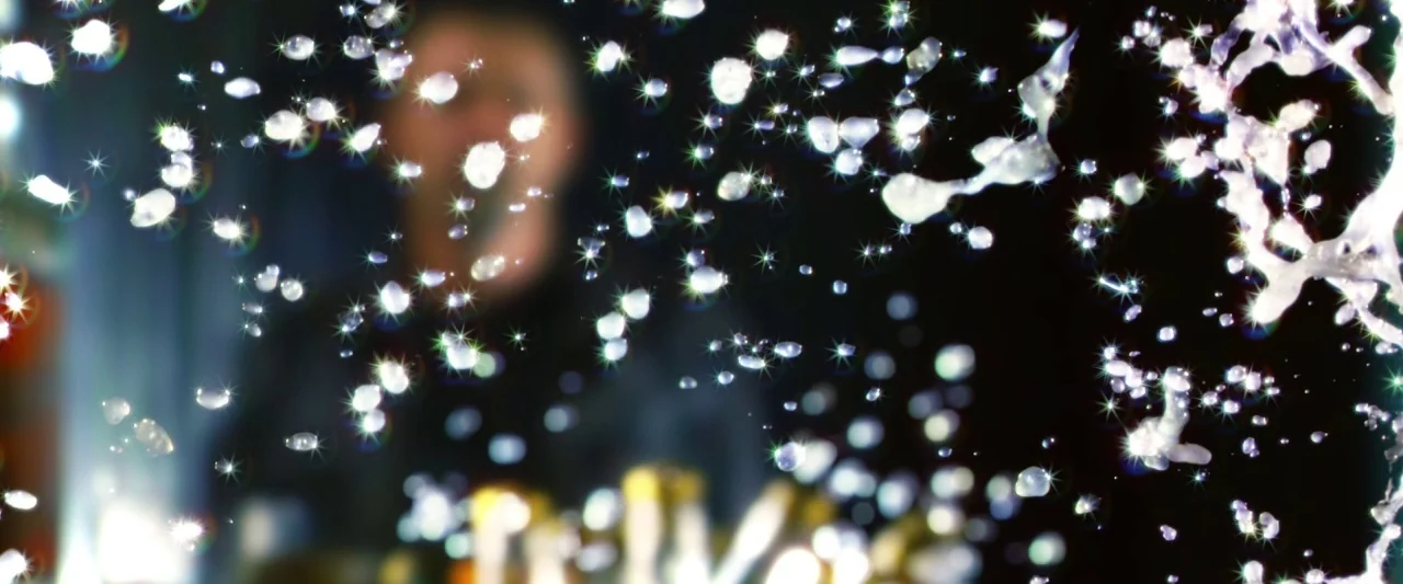 Dredd (2012) movie still: closeup — A dense spray of crystalline water droplets is captured in mid-air against darkness. The droplets exhibit sharp…