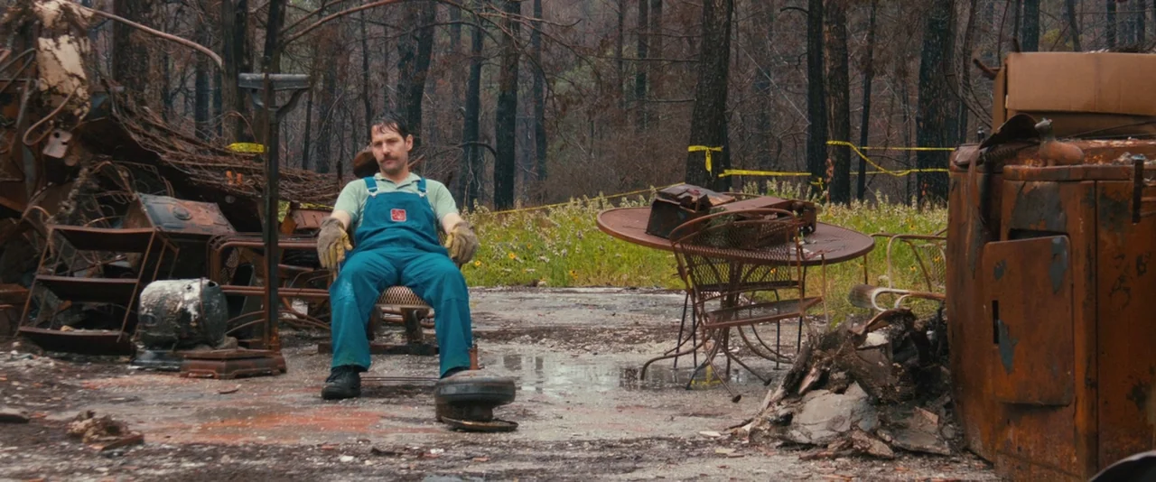 Prince Avalanche (2013) movie still: medium — A clearing in a forest contains charred remains of furniture and household objects. A man in work…