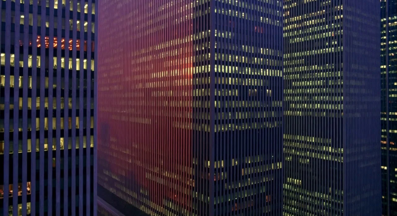 Koyaanasquatsi (1982) movie still: establishing — Three modern skyscraper facades stand vertically, showing grid patterns of glass and steel. Sunset…