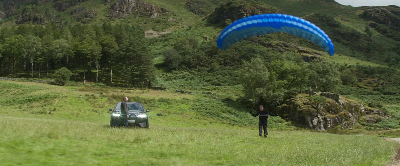 Mission: Impossible – Dead Reckoning Part One (2023) movie still: wide — A green grassy valley sits below rolling hills with a treeline on the left.…