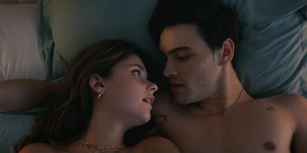 My Fault (2023) movie still: closeup — A couple lies in bed on teal-colored bedding under dim ambient light. They face each other closely while…