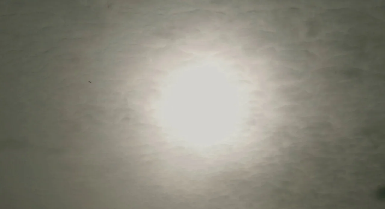 Antiviral (2012) movie still: establishing — A vast layer of overcast sky fills the frame with textured cloud formations. The sun is visible as a…