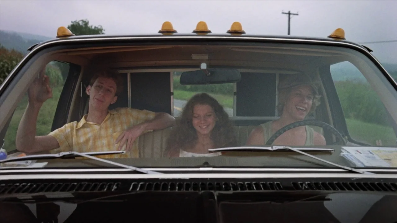 Friday the 13th Part 2 (1981) movie still: medium — Three young adults sit in the front bench seat of a pickup truck. They are traveling along a…