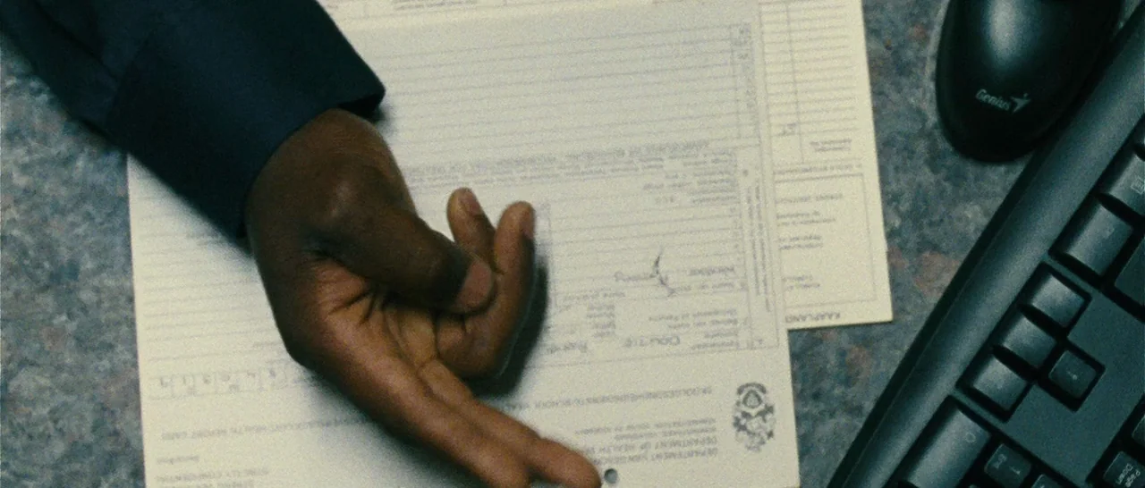 Message From The King (2016) movie still: closeup — An office desktop surface displays a printed medical report next to a black keyboard. A…