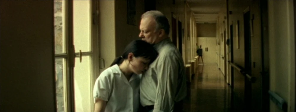 I Stand Alone (Seul Contre Tous) (1998) movie still: medium — A long hospital corridor features a window along one side with a tiled floor. A woman…