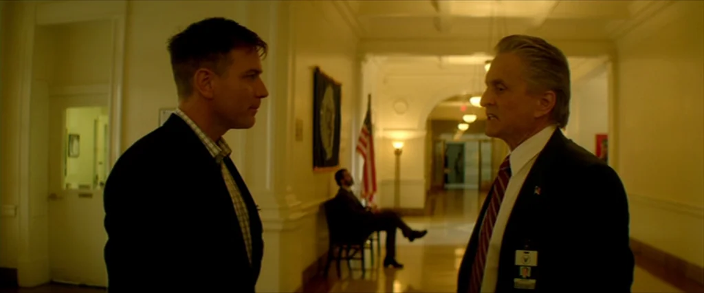 Haywire (2011) movie still: medium — A long hallway in a government building with cream walls and marble floors. Two men face each other in the…