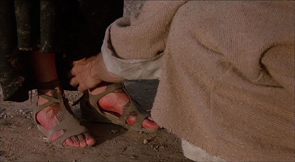The Last Temptation Of Christ (1988) movie still: closeup — An arid, sandy ground provides the setting for a close interaction between two people.…