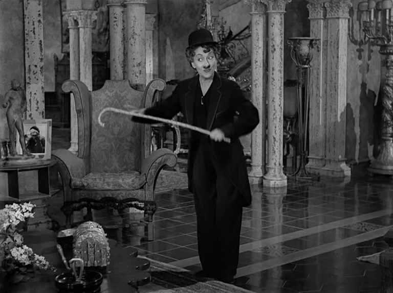 Sunset Boulevard (1950) movie still: fullbody — A spacious room features marble columns and an ornate armchair on a tiled floor. A woman dressed as…