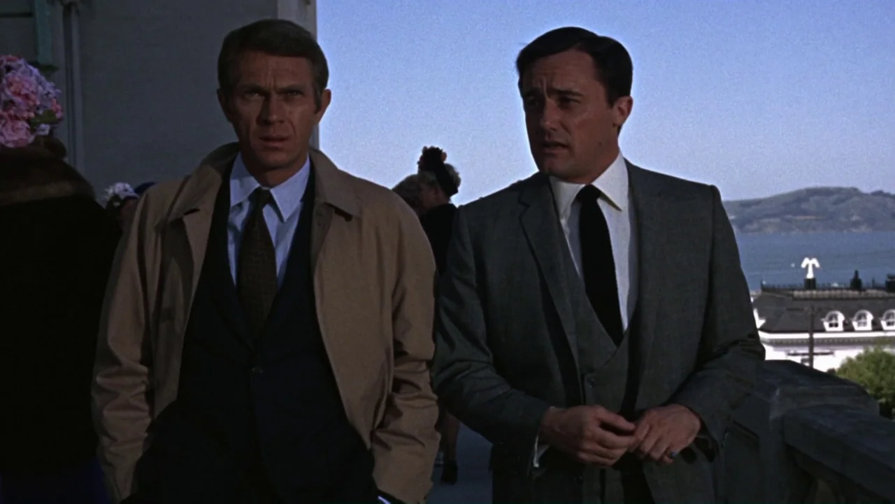 Bullitt (1968) movie still: medium — A stone terrace overlooks a body of water with distant hills on the horizon. Two men in formal business attire…
