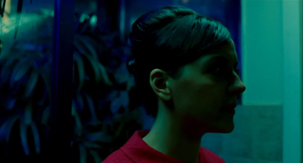 Heartbeats (Les Amours Imaginaires) (2010) movie still: closeup — A dark indoor space features a wall with a textured surface and out-of-focus…