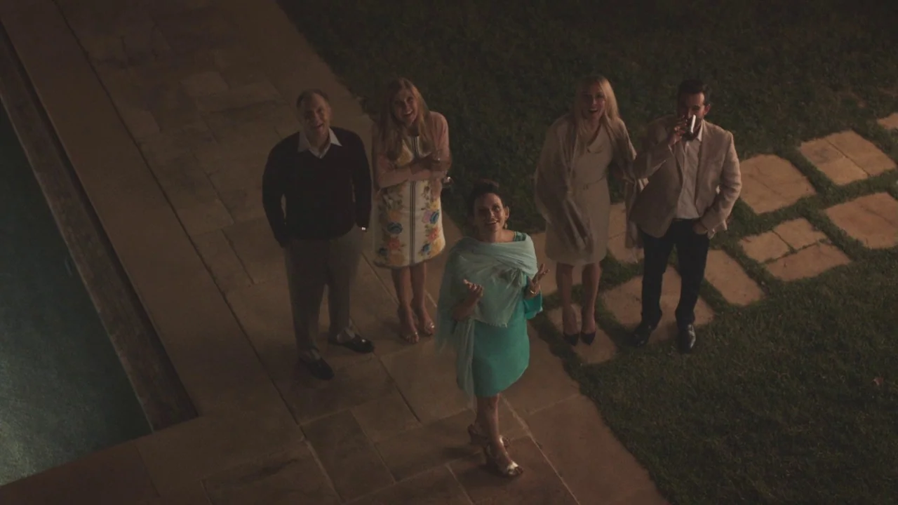 Beatriz at Dinner (2017) movie still: wide — A group of five people stand on a stone patio at night near a pool. They look upward at something…