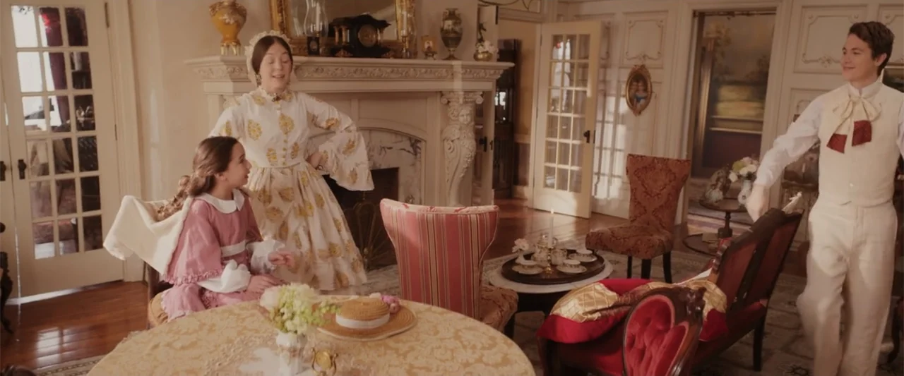 I Heard the Bells (2022) movie still: medium — An opulent 1800s parlor features an ornate fireplace, patterned furniture, and polished wooden…