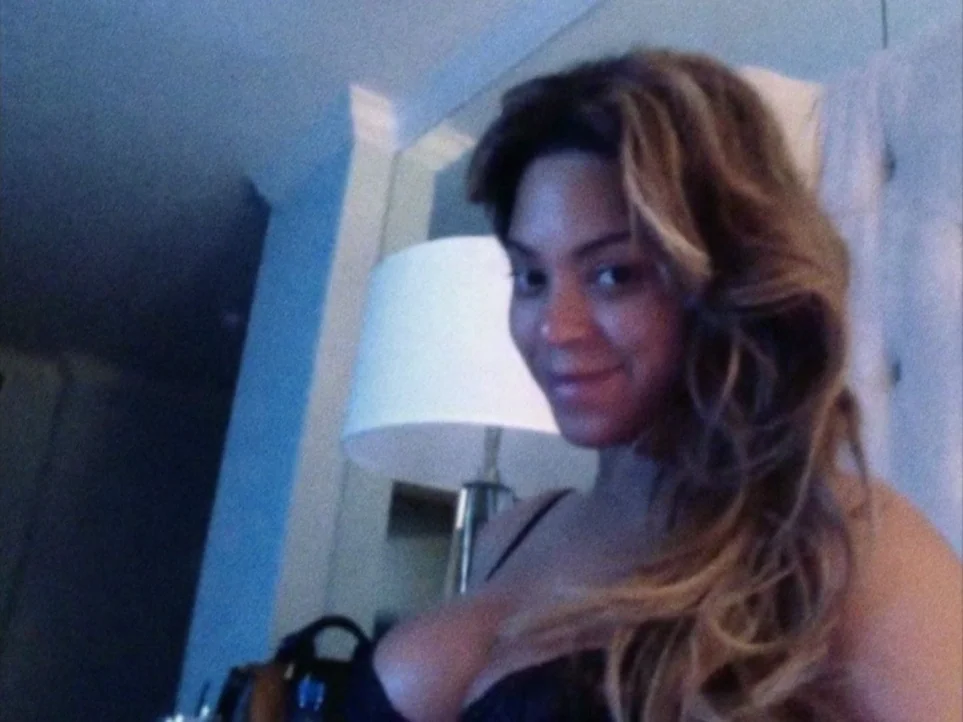Lemonade (2016) movie still: closeup — A dimly lit room features a white lampshade near a wall in the background. A woman with long wavy hair looks…