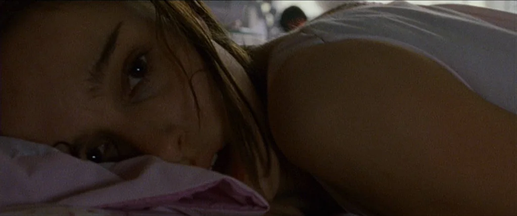 Black Swan (2010) movie still: closeup — A woman rests her head on a pillow inside a dimly lit bedroom space. The subject is shown in a close…
