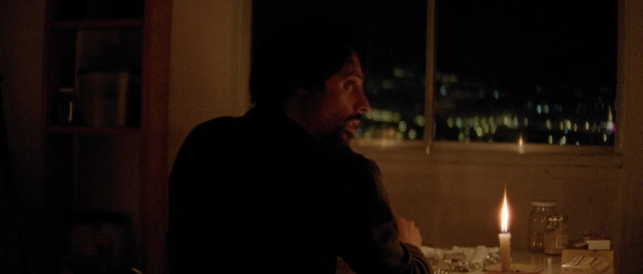 Arabian Nights: Volume 2 The Desolate One (2015) movie still: medium — A dimly lit interior space at night overlooks a distant, out-of-focus city…