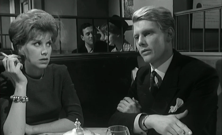 The Servant (1963) movie still: medium — A dark restaurant booth features a man and woman sitting opposite each other. The woman holds a lit…