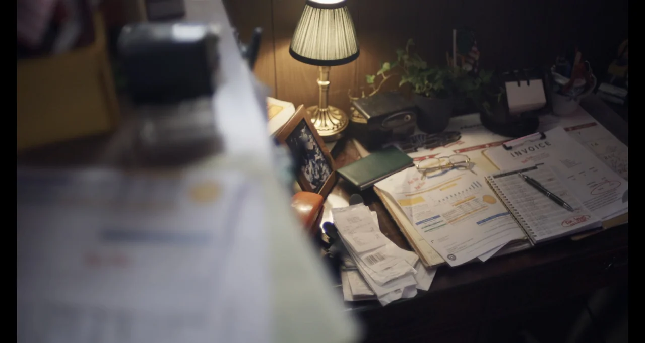 Hunted by My Husband: The Untold Story of the DC Sniper (2025) movie still: medium — A cluttered wooden desk holds an open notebook, receipts,…