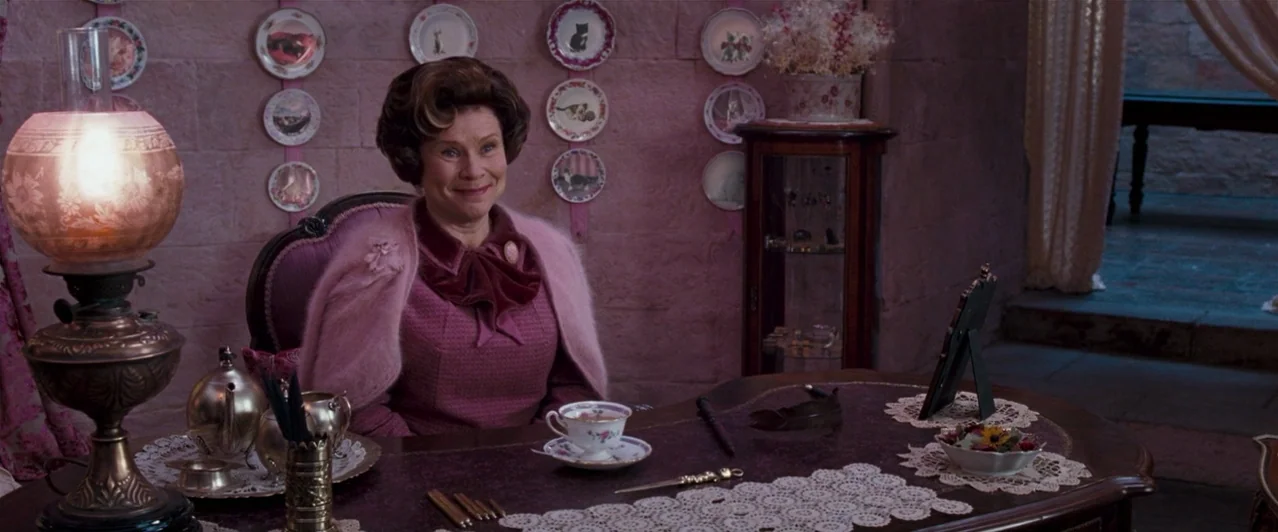 Harry Potter & The Order of the Phoenix (2007) movie still: medium — An office with pink-painted walls decorated with hanging plates and a lit…