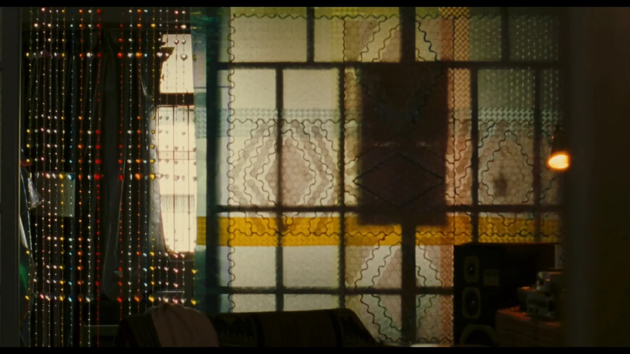 Millennium Mambo (2001) movie still: establishing — A domestic space with decorative glass beads and a patterned translucent curtain over windows. A…