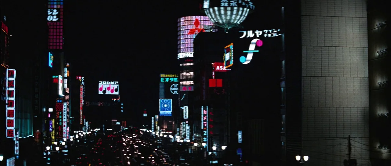 You Only Live Twice (1967) movie still: establishing — A dense urban night scene features a Tokyo street filled with glowing neon signs. Numerous…