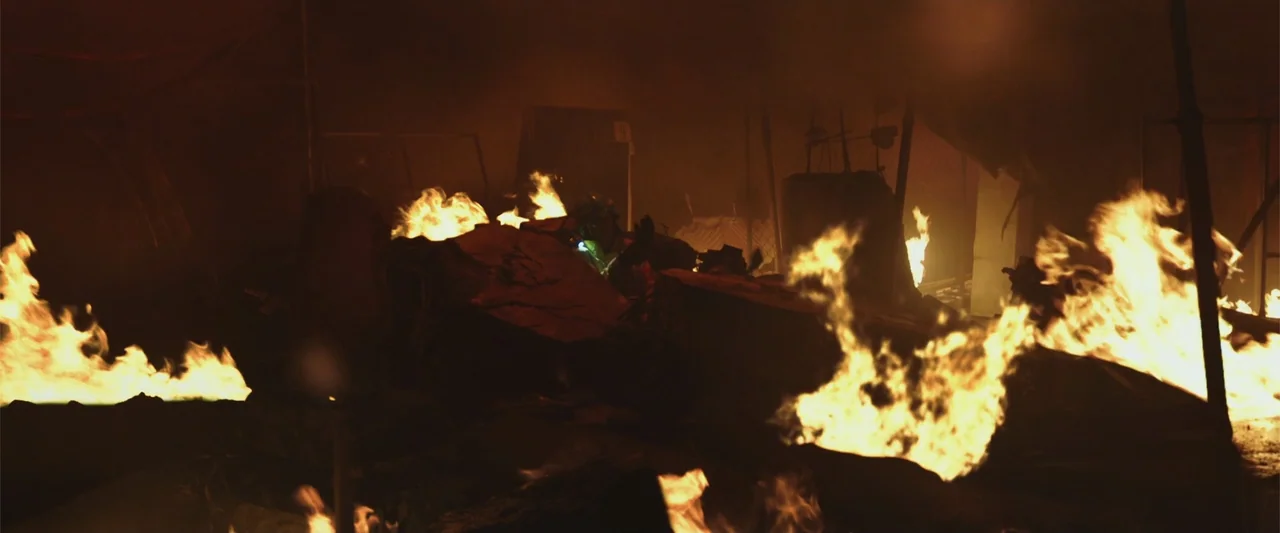Along with the Gods: The Two Worlds (2017) movie still: wide — An outdoor area filled with dark debris and smoke is engulfed by multiple fires. A…