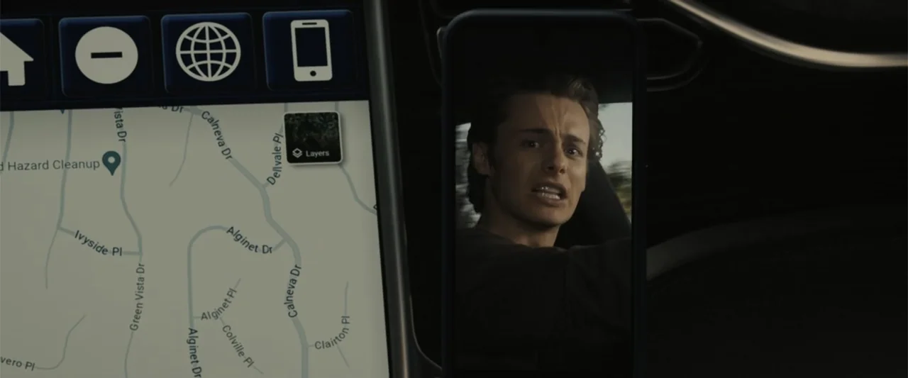 Afraid (2024) movie still: medium — A modern car dashboard displays a digital navigation map next to a smartphone screen. A young man is visible on…